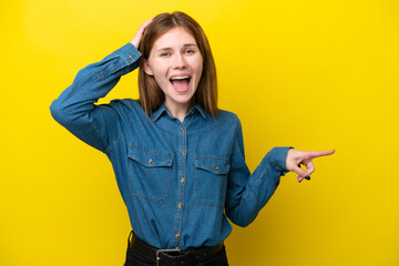 Young English woman isolated on yellow background surprised and pointing finger to the side