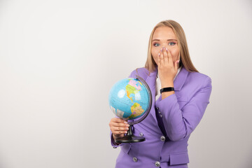 Blonde teacher holding globe and covering her mouth