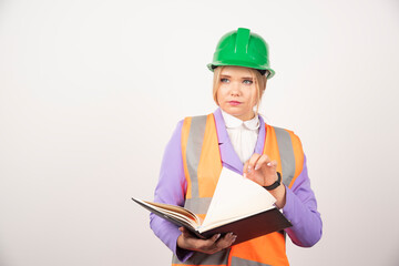 Young female builder in helmet with tablet on white background