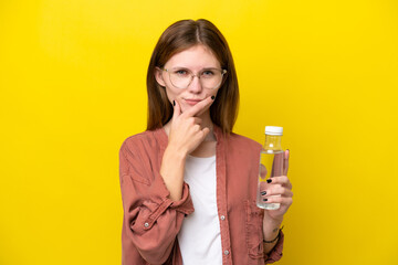 Young English woman with a bottle of water isolated on yellow background thinking