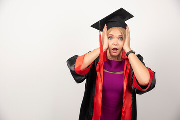 Female student in gown looking surprised on white background