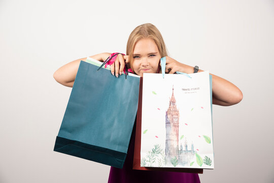 Blonde Woman Hiding Behind Shopping Bags