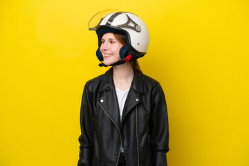 Young English woman with a motorcycle helmet isolated on yellow background looking side