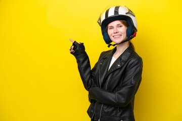 Young English woman with a motorcycle helmet isolated on yellow background pointing finger to the side