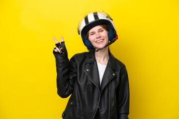 Young English woman with a motorcycle helmet isolated on yellow background smiling and showing victory sign