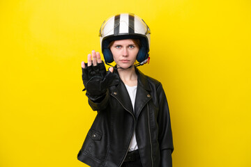 Young English woman with a motorcycle helmet isolated on yellow background making stop gesture