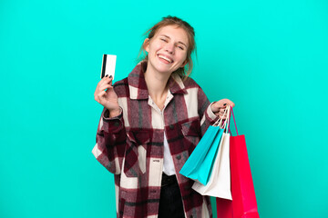 Young English woman isolated on blue background holding shopping bags and a credit card