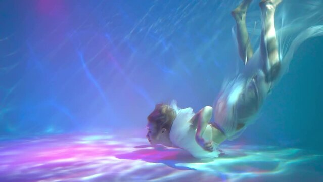 Slow Motion Underwater woman portrait in swimming pool.