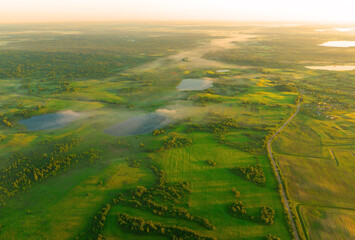 Foggy sunrise. Nature at dawn in fog, aerial view. Rural landscape with a small lake in forest....