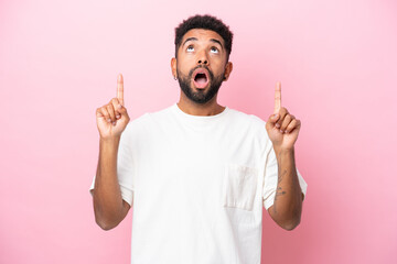 Young Brazilian man isolated on pink background surprised and pointing up