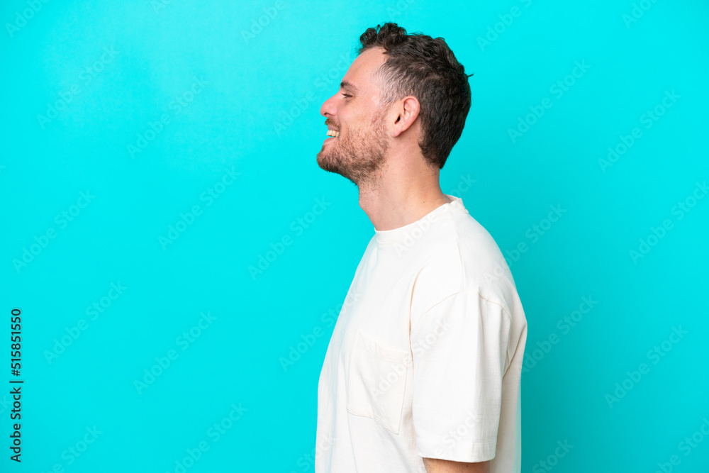 Wall mural Young Brazilian man isolated on blue background laughing in lateral position