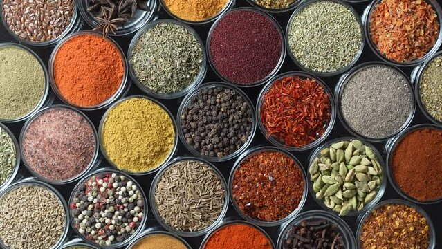 Assortment of aromatic spices, seeds and dry herbs for cooking food on background rotating in smal glass bowls rotating, close up, top view
