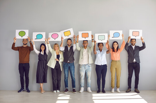 Full body length group happy diverse multiracial multiethnic people showing various paper sheets, cards and banners with pictures of different speech clouds and message bubbles. Communication concept