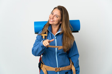 Middle age mountaineer woman with a big backpack over isolated background pointing front with happy expression