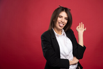 Young businesswoman making silly face on red background