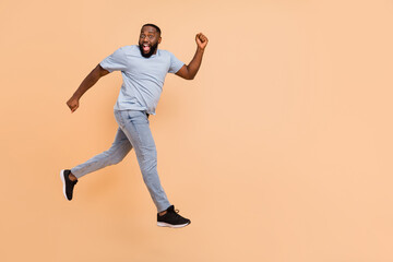 Fototapeta na wymiar Full length body size view of attractive cheerful sportive guy jumping having fun running isolated over beige pastel color background