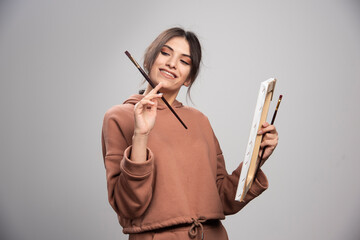 Fototapeta premium Beautiful artist posing with paint brush and canvas