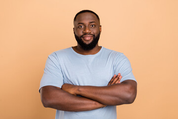 Portrait of attractive cheery content funky guy body guard folded arms isolated over beige pastel color background