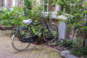 Fototapeta na wymiar Bicycle parked in front of a red brick building, Amsterdam city neighborhood. Holland Netherlands.