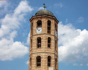 Fototapeta na wymiar Agios Stefanos church belfry, Greece, Arnaia Halkidiki. Cross, weather vane and clock. Under view