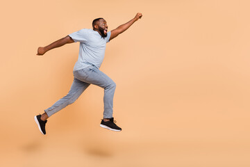 Fototapeta na wymiar Full length body size view of attractive cheerful crazy guy jumping striving copy space isolated over beige pastel color background