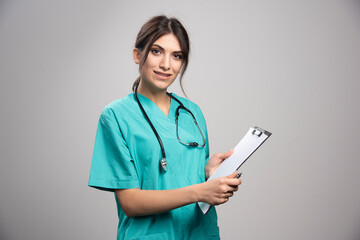 Female doctor holding clipboard on gray background