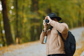 Black man standing on a road and take a photo on a professional camera