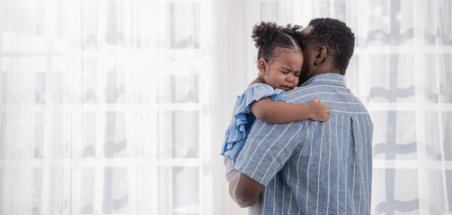Portrait of american african father daughter hugging laughing in living room. addy and cry little girl spending leisure time at home. Single dad, family lifestyle father's day concept banner