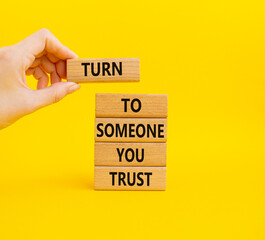 Turn to Someone you trust symbol. Wooden blocks with words Turn to Someone you trust. Beautiful yellow background. Businessman hand. Business and Turn to Someone you trust. Copy space.