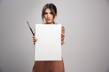 Young woman showing paint brushes and canvas