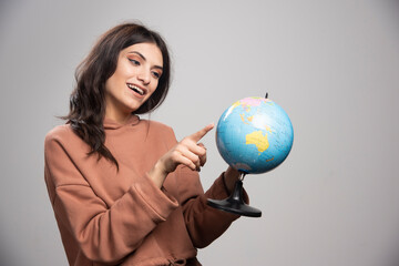 Brunette woman pointing at small place on globe