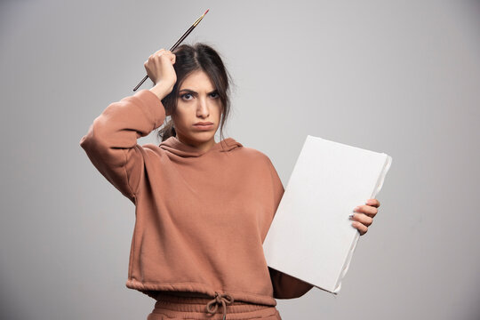 Young woman holding paint brushes and canvas