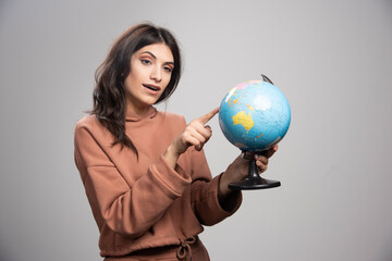Fototapeta premium Brunette woman pointing at small place on globe