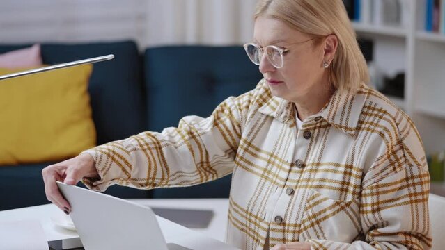 Woman in her 50s working on laptop from home, financial analyst, freelancer