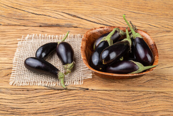 Tiny baby eggplants in a bowl over wooden table