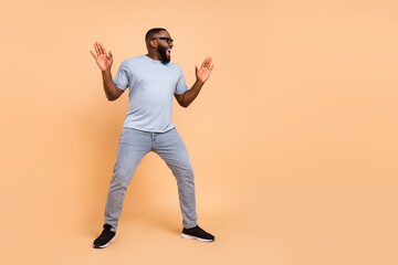 Fototapeta na wymiar Full length body size view of attractive cheerful guy dancing having fun isolated over beige pastel color background