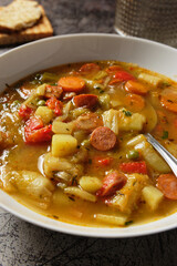 Vegetable soup with sliced Debrecziner sausages, a spicy Hungarian boiled sausage specialty. Close up view.