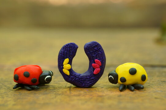 Figurines of two ladybugs made of plasticine close-up. Between them is a horseshoe.