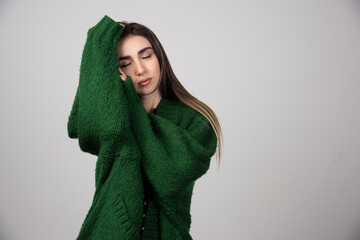 Young woman in green sweater sleeping on gray background