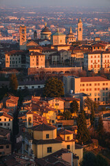 Fototapeta na wymiar The city of Bergamo, its historic center and the hills, with the lights of the sunset, at the end of a winter day - February 2022.