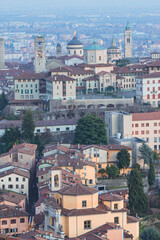 Fototapeta na wymiar The city of Bergamo, its historic center and the hills, with the lights of the sunset, at the end of a winter day - February 2022.