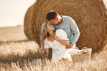 Happy couple sitting on bale in farmland
