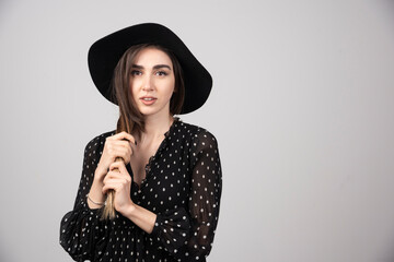 Young woman in black hat playing with her hair