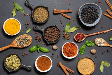Set of aromatic spices and herbs on black stone background. 