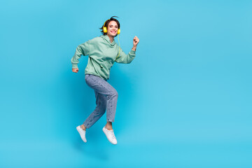 Obraz premium Full body profile photo of sweet young brunette lady run wear headphones pullover jeans shoes isolated on blue background