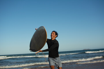Smiling man playing with surfboard