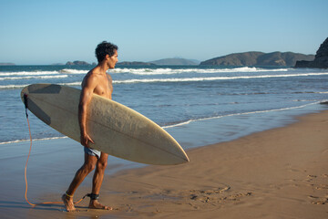 male athlete on his side, holding a surfboard looking out to sea