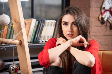 A young woman model in red blouse sitting and posing