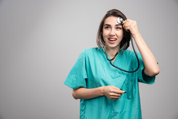 Female doctor with stethoscope laughing on gray background