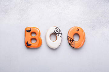 Text BOO from gingerbread cookies on white stone background. Halloween concept